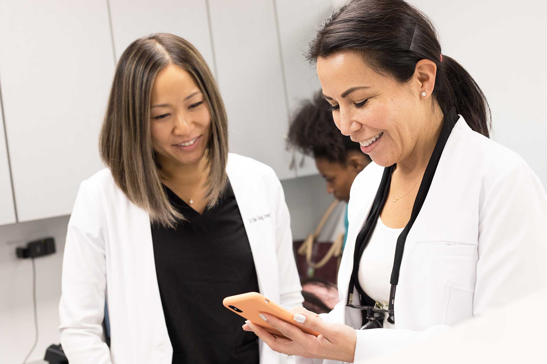 Dr. Estrada and a team member look at a smart phone together, both smiling.