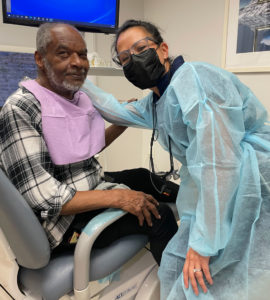 Dental Artist team member leans in, hand on patient Sonelius Smith's shoulder. Both appear proud.